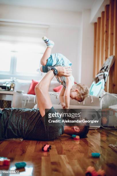 single father spending quality time with baby son in living room - child picking up toys stock pictures, royalty-free photos & images