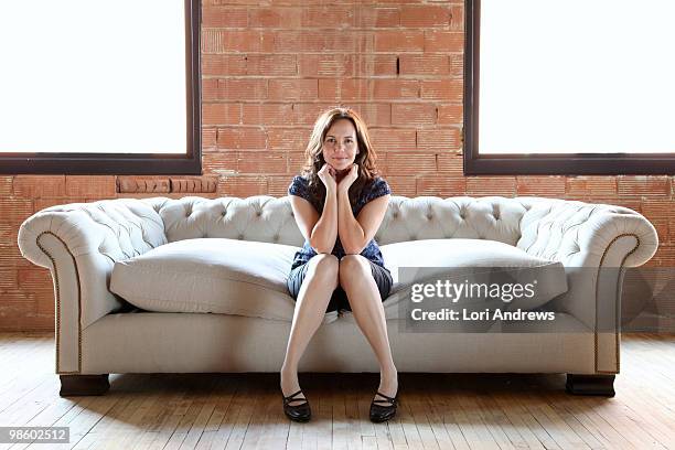 woman on tufted sofa - frau sitzt stock-fotos und bilder