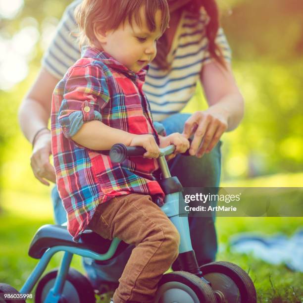 young mother and her son on a runbike in summer park - artmarie stock pictures, royalty-free photos & images