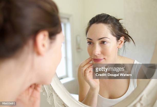 woman looking at self in mirror. - see foto e immagini stock