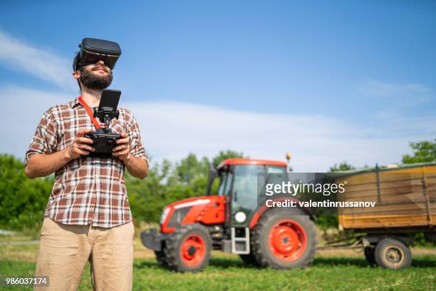 farmer flying a drone over a field, and using vr headset - farmer drone stock pictures, royalty-free photos & images