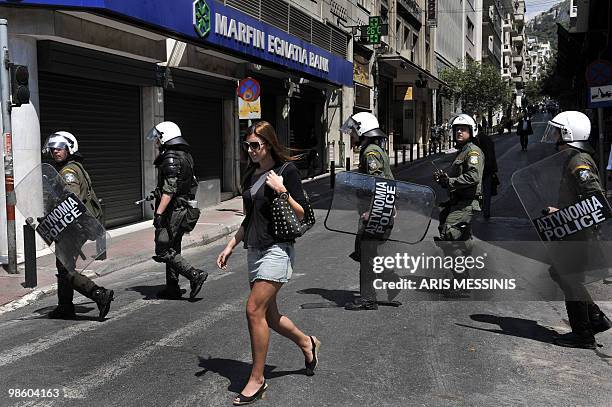 Woman walks in front of riot police during a demonstration in central Athens on April 22, 2010. Greek civil servants staged the fourth 24-hour strike...