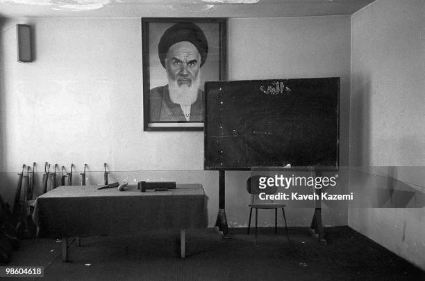German made G-3 automatic assault rifles rest against a wall under watchful eyes of Ayatollah Khomeini where training sessions for Basiji men are...