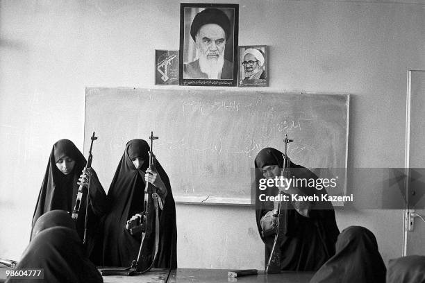 Basiji women wearing black chadors, familiarise with AK-47, an automatic assault rifle, in a school classroom in west Tehran, as part of mass...