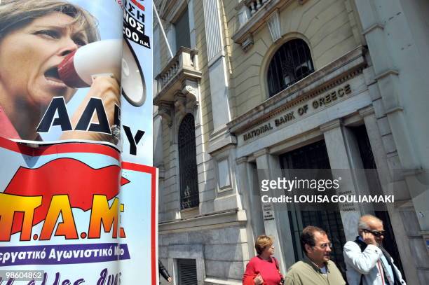 People walk by a poster calling for strike, next to a National Bank of Greece in Athens on April 22, 2010. Greek civil servants staged on Thursday...