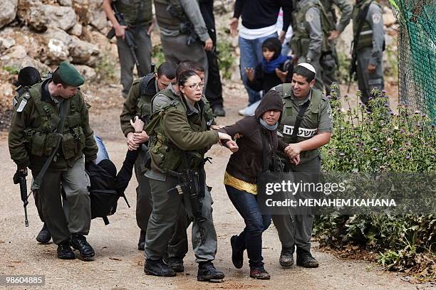 Israeli border policemen carry away foreign activists protesting together with Palestinians against the extension of Israel's controversial...