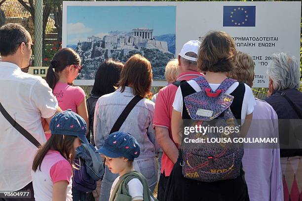 Tourists listen to their guide in front of a picture of the Acropolis in Athens during a 24- hour strike that has seen the archaeological site closed...