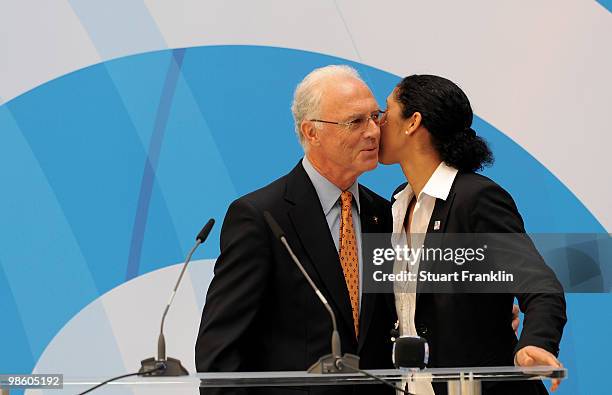 Franz Beckenbauer, chairman of the FIFA U20 and U17 Women's World Cup Committee is kissed by Steffi Jones, chairman of the Local Organising Committee...