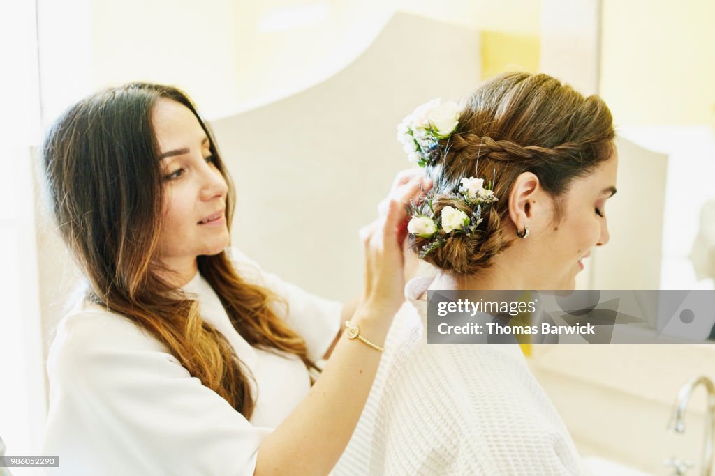 Female friend helping bride put flowers in hair before wedding