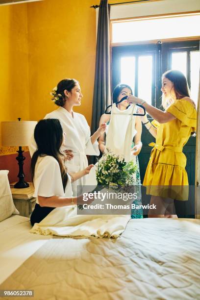 bride and friends admiring wedding dress in hotel room before ceremony - societetsskönhet bildbanksfoton och bilder