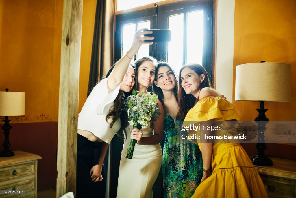 Smiling friends taking a selfie with bride before wedding ceremony