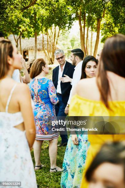 smiling friends gathered in discussion after outdoor wedding ceremony at tropical resort - belleza de sociedad fotografías e imágenes de stock