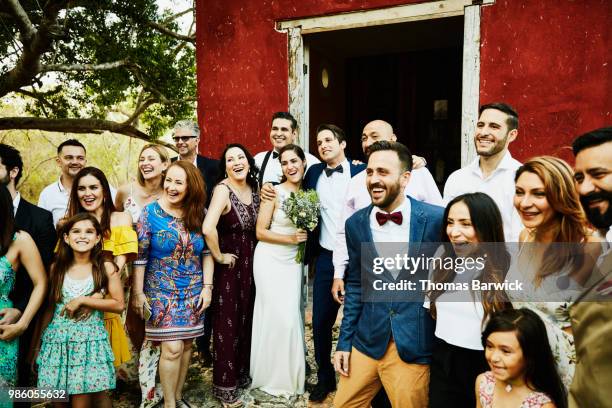 laughing and smiling wedding party posing for group photo in front of chapel after wedding ceremony - wedding party stock-fotos und bilder