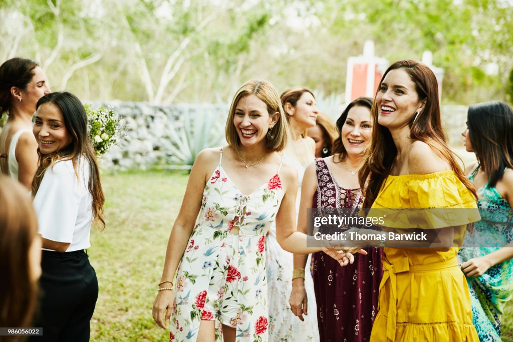 Laughing female friends in discussion during outdoor wedding reception