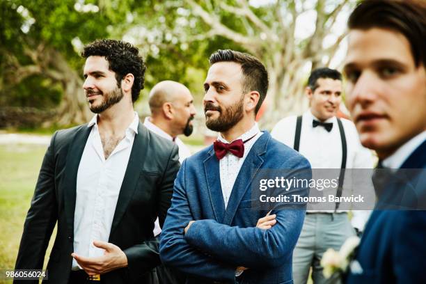 Male friends hanging out together during outdoor wedding reception