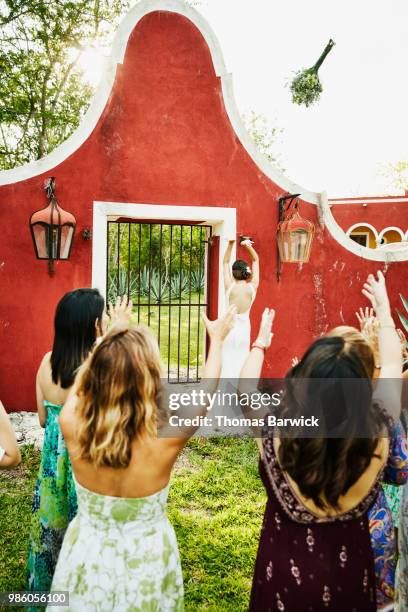 bride throwing bouquet to wedding guests during outdoor reception at tropical resort - society beauty stock pictures, royalty-free photos & images