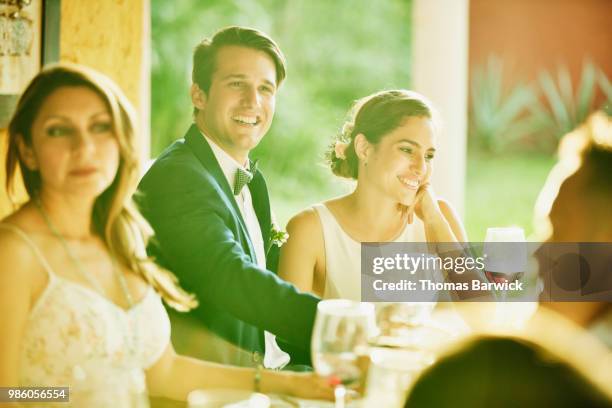 smiling bride and groom enjoying dinner with friends during outdoor reception - society beauty 個照片及圖片檔