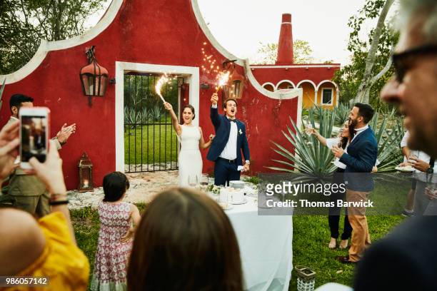 bride and groom celebrating with sparklers after cutting cake during outdoor wedding reception - hot mexican girls stock-fotos und bilder