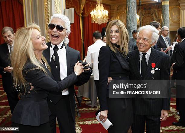 Fashion designer flanked by chief editor of the French edition of Vogue, Carine Roitfeld looks at German fashion designer Karl Lagerfeld dancing with...