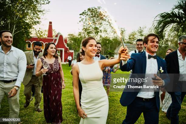 bride and groom holding sparkler while celebrating during outdoor wedding reception - wedding reception stock pictures, royalty-free photos & images