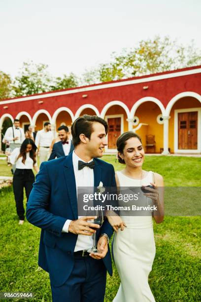 smiling bride and groom walking arm in arm on grounds of tropical resort during wedding reception - society beauty 個照片及圖片檔