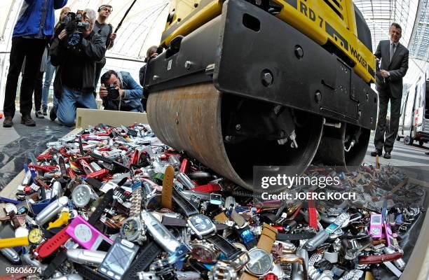 Customs officers use a roller to destroy counterfeit MP3 players and watches at the airport in the southern German city of Munich on April 22, 2010....