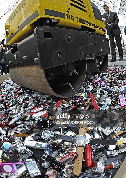 Customs officers use a roller to destroy counterfeit MP3 players and watches at the airport in the southern German city of Munich on April 22, 2010....