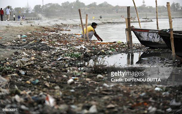 An Indian boatman sits near the polluted river waters of The Ganges at Sangam, the confluence of the Ganges, Yamuna and mythical Saraswati rivers in...