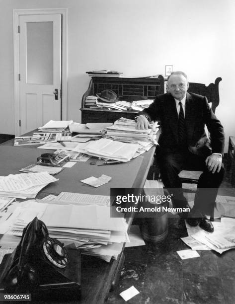 Portrait of American politician Senator Harry F Byrd as he sits at a desk crowded with papers, a number of which have fallen to the floor about his...