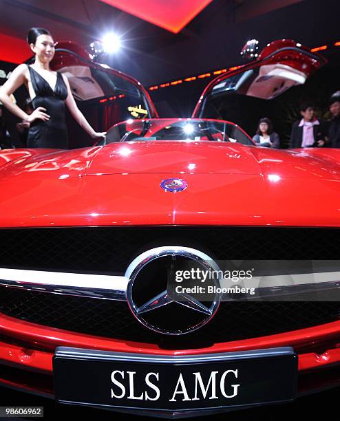 Model poses next to Daimler AG 's Mercedes SLS AMG vehicle on display during a media event unveiling the company's vehicles for the Beijing Auto Show...