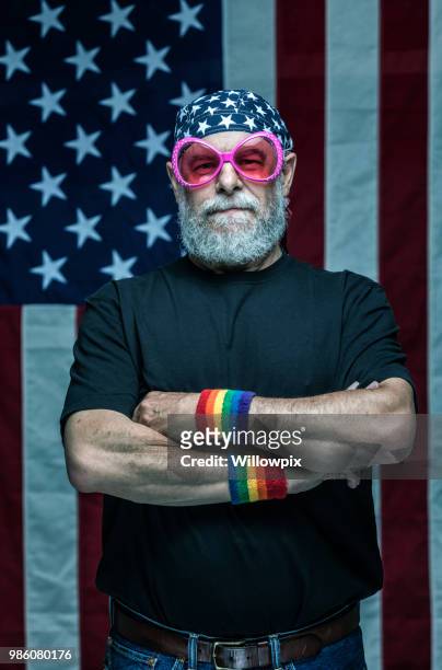 usa senior erwachsenen militärischen veteran regenbogen pride armbänder und bizarre rosa sonnenbrille tragen - gay flag stock-fotos und bilder