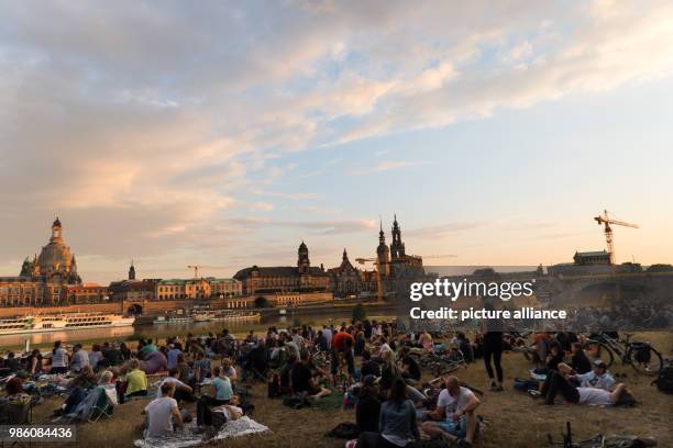 June 2018, Germany, Dresden: Numerous people sit at sundown in a park and listen to the concert. The concert of 'Queens of the Stone Age' at the...