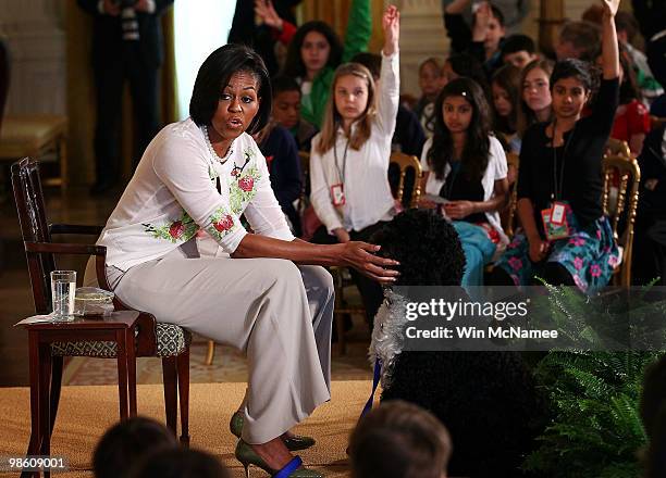 First lady Michelle Obama pets the family dog Bo as she speaks to children in the East Room of the White House April 22, 2010 in Washington, DC. Mrs....