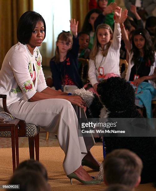 First lady Michelle Obama pets the family dog Bo as she speaks to children in the East Room of the White House April 22, 2010 in Washington, DC. Mrs....