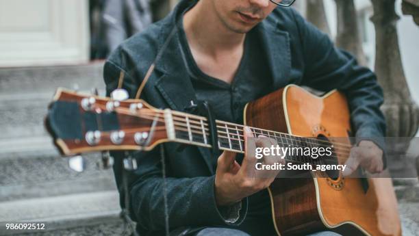 young man with differing abilities playing acoustic guitar outdoors - soloist stock pictures, royalty-free photos & images
