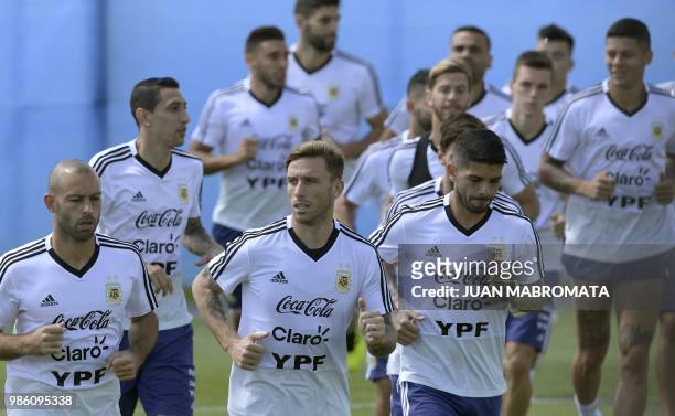 Argentina's midfielder Javier Mascherano, midfielder Lucas Biglia and midfielder Ever Banega lead teammates while warming-up during a training...