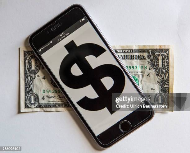 Symbol photo on the topic pay with the smartphone. The picture shows the dollar logo on a smartphone display. The smartphone lies on a one dollar...