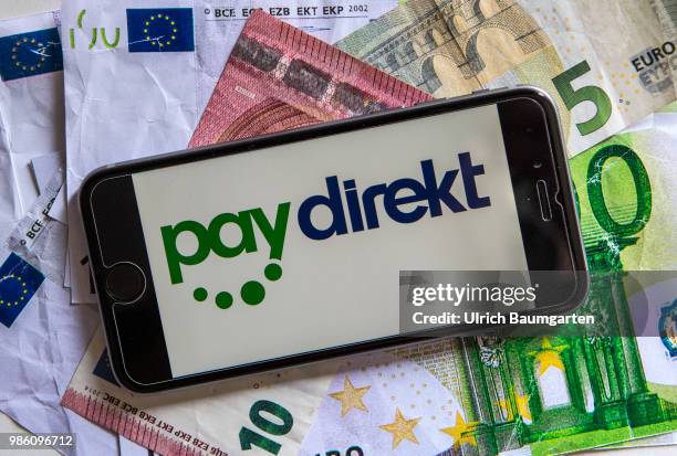 Symbol photo on the topic pay with the smartphone. The picture shows the paydirekt logo on a smartphone display. The smartphone lies on euro...