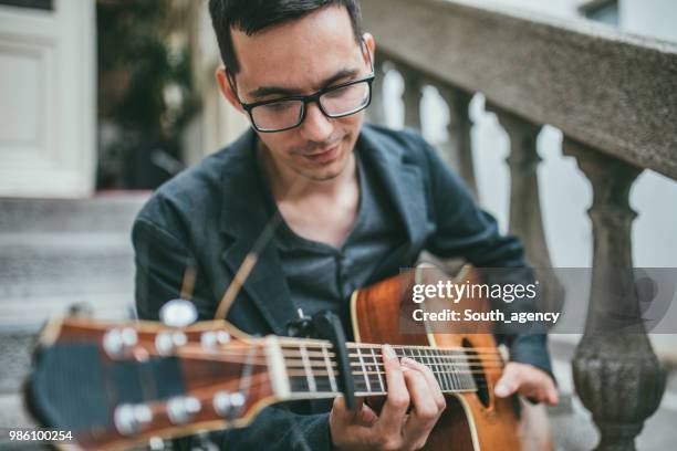 young man with differing abilities playing acoustic guitar - soloist stock pictures, royalty-free photos & images