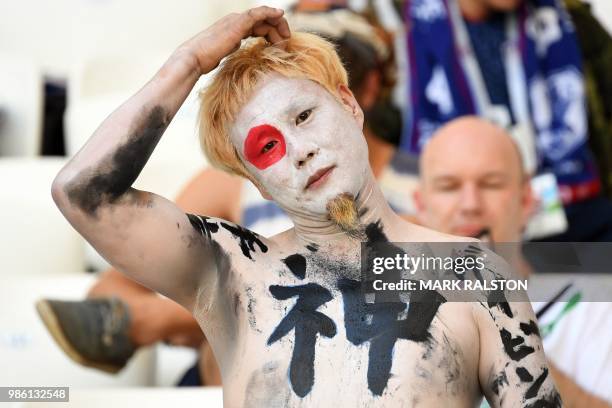 Japan's fan with the national flag painted on his face and ideograms on the chest gestures as he waits before the Russia 2018 World Cup Group H...