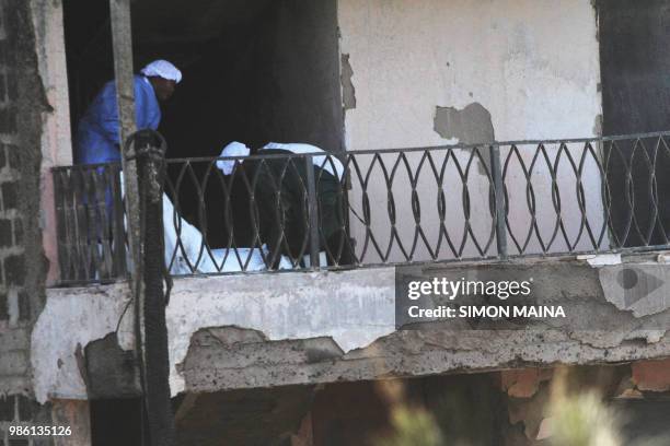 Kenyan forensic experts investigate in the grounds of the smouldering debris following a fire that gutted the timber dealership at the Gikomba market...