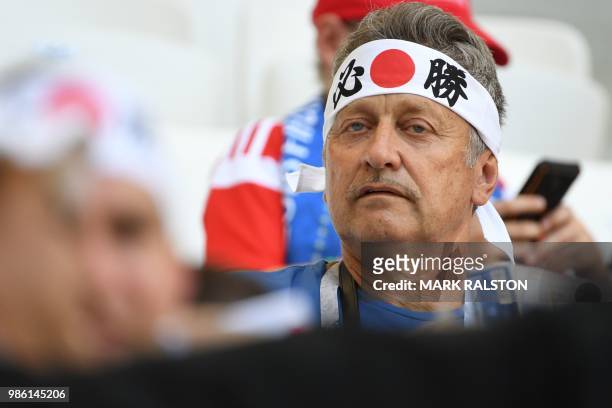 Japan's fan with the national flag and ideograms printed on a headband looks on as he waits before the Russia 2018 World Cup Group H football match...