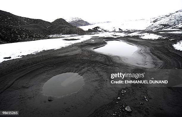 Glacial water accumulates in small pools on volcanic ash at the base of the Myrdalsjokull glacier, which is part of the ice cap sealing the Katla...