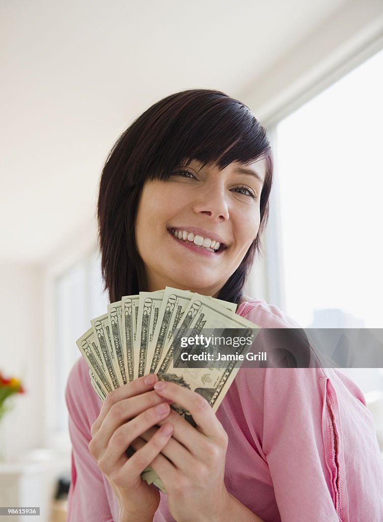 Young woman holding money, smiling