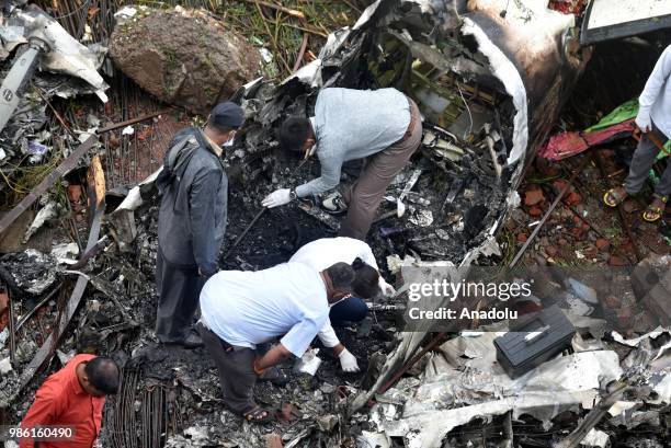 Indian firemen and aviation officials inspect the wreckage of a plane that crashed into a construction site, killing five people, in Mumbai on June...