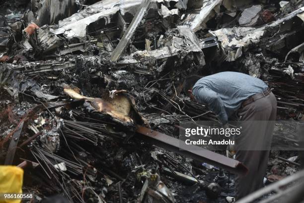 Indian firemen and aviation officials inspect the wreckage of a plane that crashed into a construction site, killing five people, in Mumbai on June...