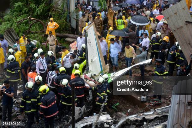 Indian firemen and aviation officials inspect the wreckage of a plane that crashed into a construction site, killing five people, in Mumbai on June...