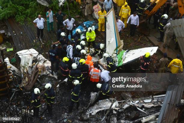 Indian firemen and aviation officials inspect the wreckage of a plane that crashed into a construction site, killing five people, in Mumbai on June...