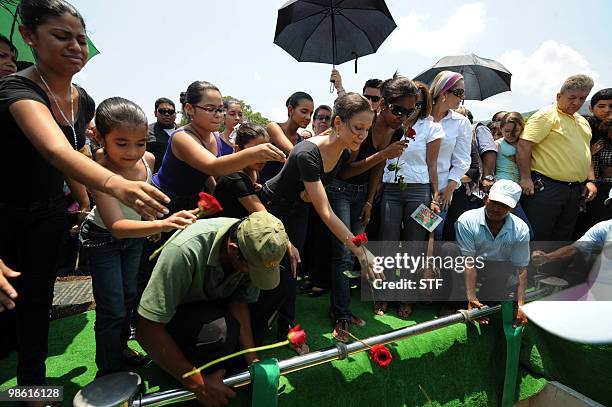 Students throw flowers into the grave during the burial of television journalist and university professor Jorge Alberto Orellana, in San Pedro Sula,...