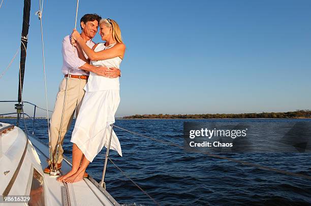 man and woman embracing at sunset on a sailboat - newoutdoors stock pictures, royalty-free photos & images